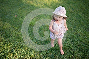 Little girl walking barefoot through the meadow