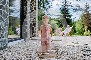 Little girl walking barefoot near the forest cotage,weekend time during summer day.