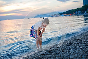 Little girl walking on beautiful ocean beach. Happy preschool child play by sunset on sea beach. Family vacations with