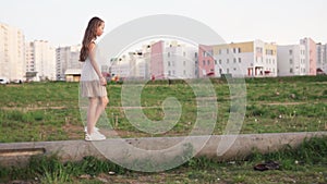 Little girl walking on concrete log on urban wasteland