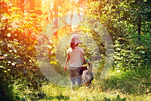 Little girl walking with dog in the forest