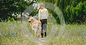 Little girl walking dog on meadow