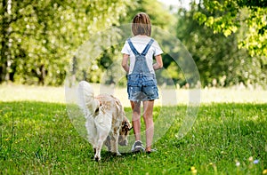 Little girl walking dog on meadow