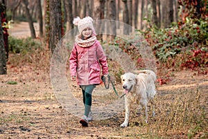 Little girl walking with dog in pine wood