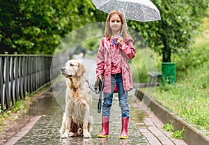Little girl walking dog in rainy park