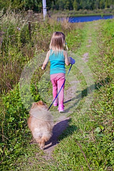 Little girl walking with her ??dog on a leash