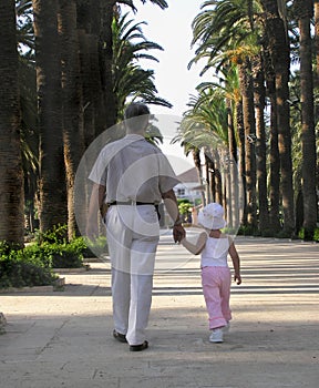 Little girl walking in a park with her grandfather