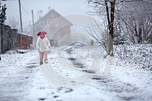 Little girl walking on snowy rural road