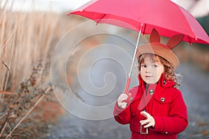 Little girl walking with umbrella, autumn day.