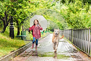 Little girl walking under rain with dog