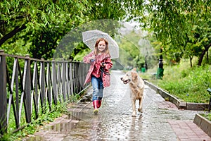 Little girl walking under rain with dog