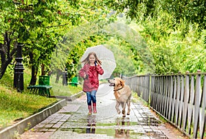 Little girl walking under rain with dog