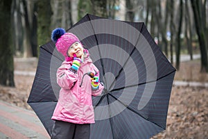 Little girl walking under umbrella in a park