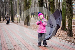 Little girl walking under umbrella in a park