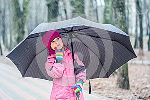 Little girl walking under umbrella in a park