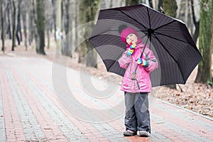 Little girl walking under umbrella in a park