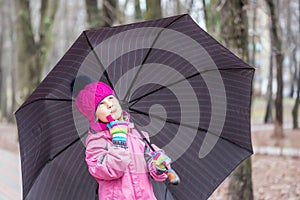 Little girl walking under umbrella in a park