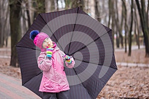 Little girl walking under umbrella in a park