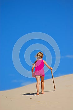 Little girl walking up sand dune