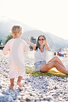 Little girl walks along the beach to her mother open arms