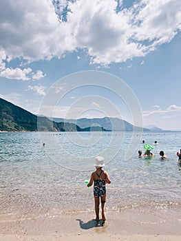 Little girl walks along the sand towards the sea. Back view