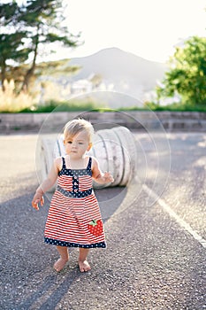 Little girl walks in the parking lot against the background of white tires