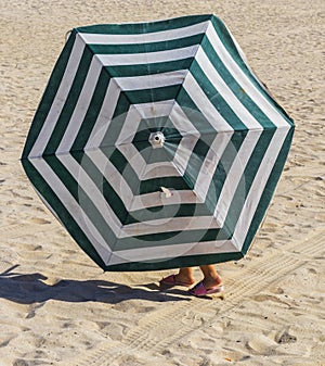 Little girl walks under old beach umbrella. Fun