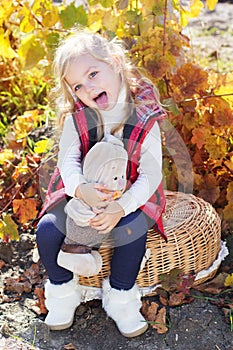 Little girl in warm clothes with toy rabbit