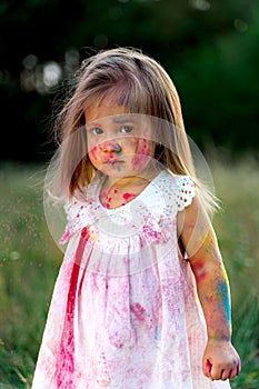 The little girl was covered in paint. a girl in a green clearing. hair up