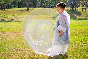 A little girl was happily standing in an umbrella against the rain