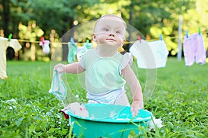 The little girl washes clothes in a green