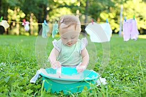 The little girl washes clothes in a small green