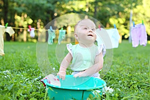 The little girl washes clothes in a small green