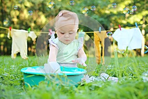 The little girl washes clothes in a small green