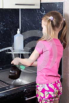 Little girl washes dishes with sponge