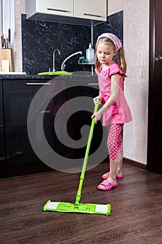 Little girl washes floor with a mop