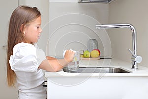 Little girl washing dish in kitchen, kid doing house chores