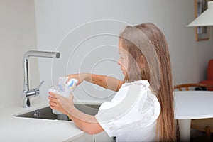 Little girl washing dish in kitchen, kid doing house chores