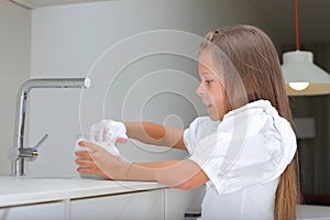 Little girl washing dish in kitchen, kid doing house chores