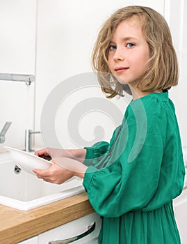 Little girl washing dishes.