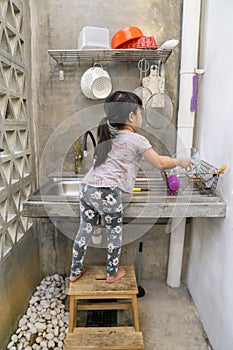 Little girl washing some dishes in her home kitchen