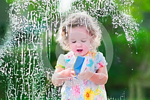 Little girl washing a window