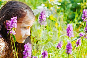 little girl watching a bee pollinate wild flowers in a field