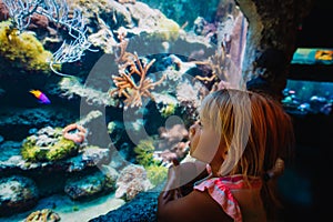 Little girl watching fishes in aquarium, kids learn underwater life