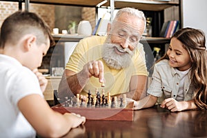 Little girl watching her brother and grandfather play chess