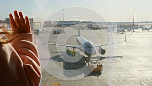 little girl watching Parked plane at the Moscow airport through the gate window. Maintenance and preparation of the