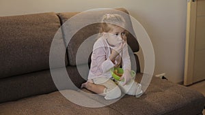 Little girl watching TV and eating chips sitting on sofa