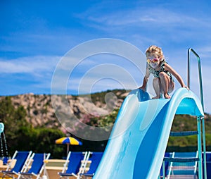 Little girl on water slide at aquapark on summer