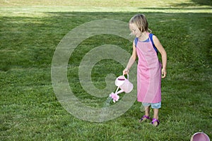 Little girl with watering can in the garden