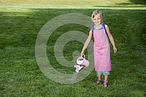 Little girl with watering can in the garden